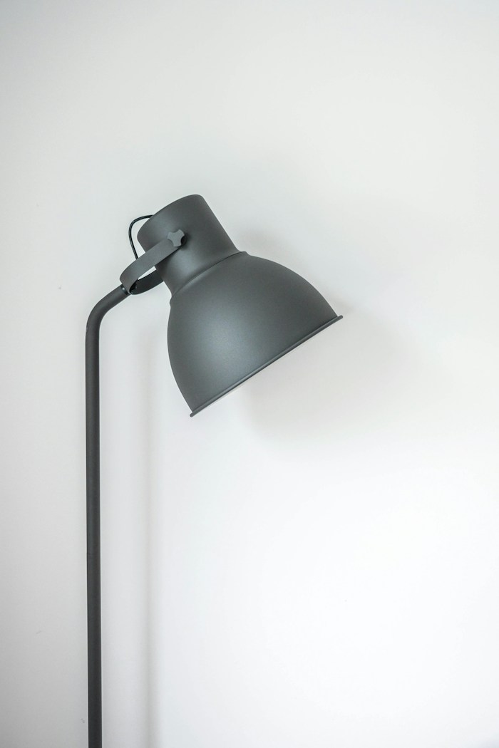 A graphite desk lamp with an angled shade against a pale wall