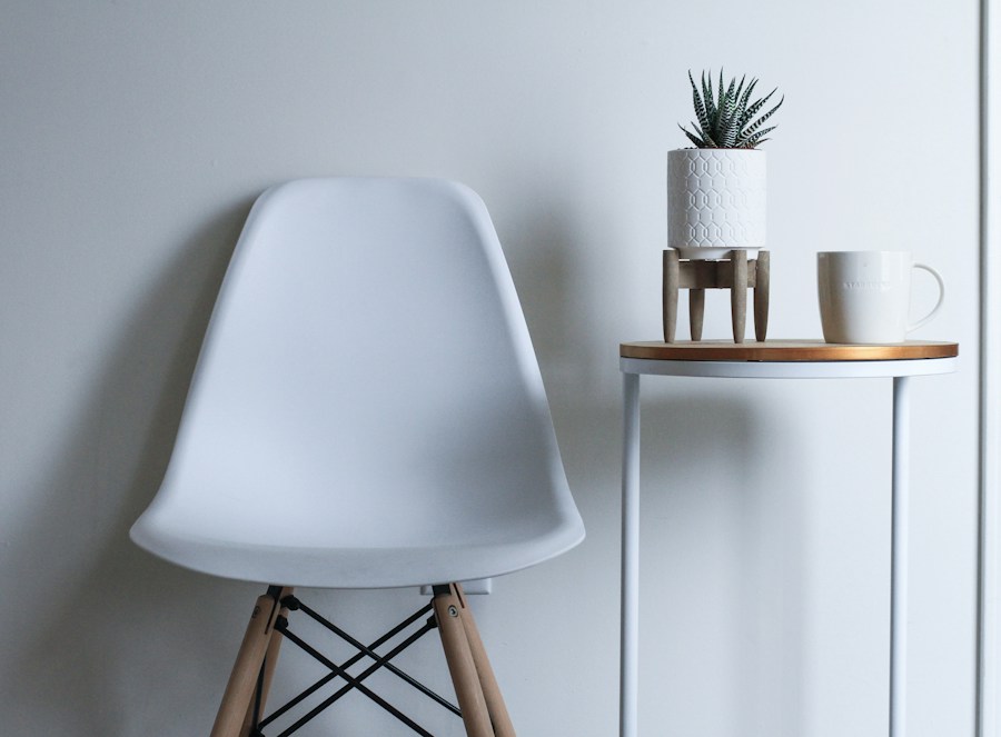 A white moulded shell chair with wooden legs beside a small table