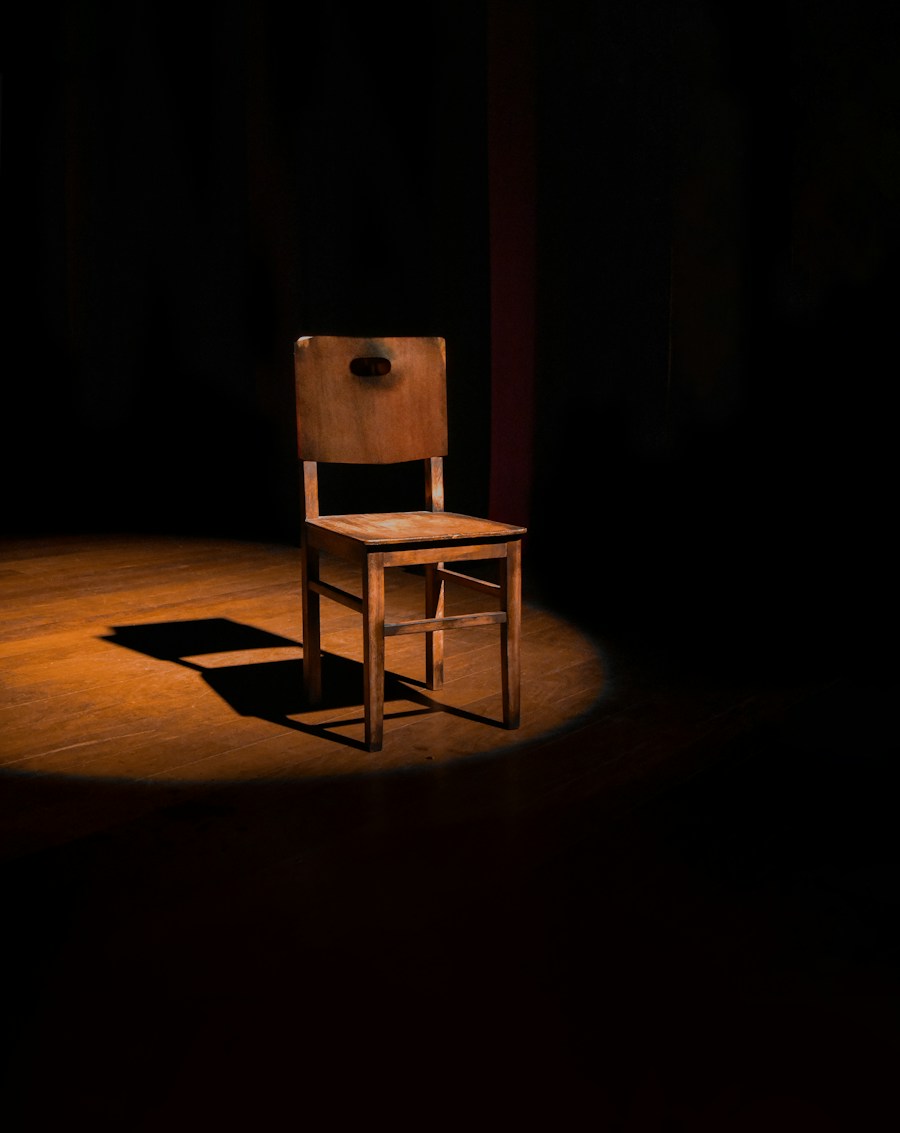 A warm wooden chair with a rectangular back in a pool of light